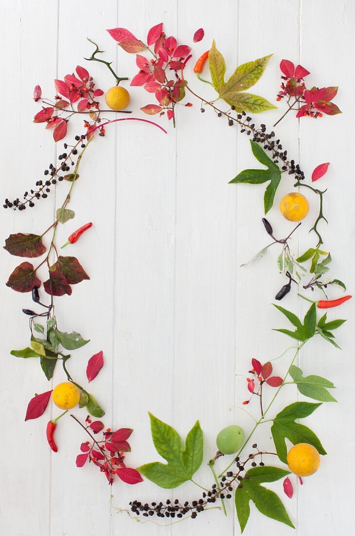 Ovaler Rahmen aus Herbstblättern, Früchten und Chilischoten