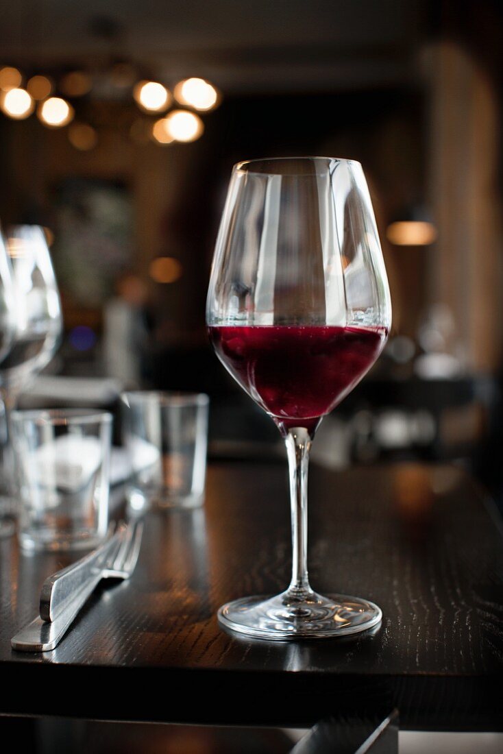 A glass of red wine on a table in a restaurant