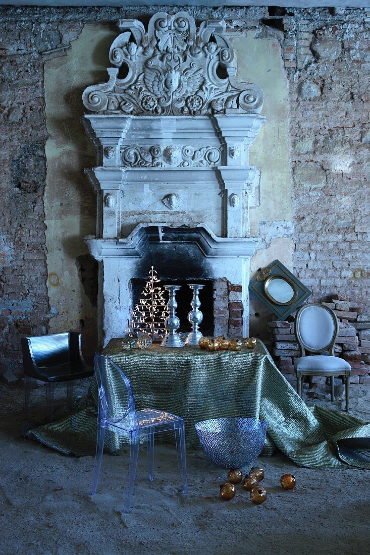 Ghost chair and Christmas arrangement on table in front of open fireplace with Greek-style, antique architectural elements in dilapidated ambiance