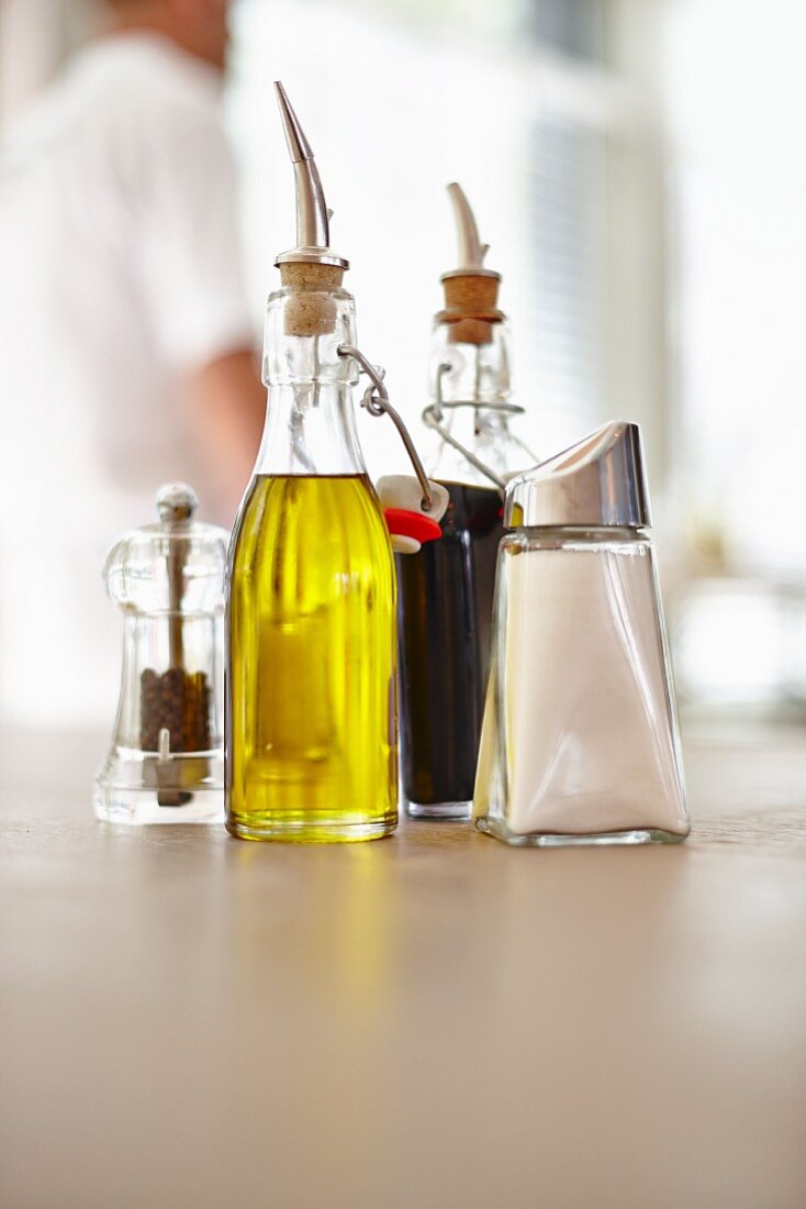 Essig- und Ölspender, Pfeffermühle und Zuckerstreuer auf Restauranttisch
