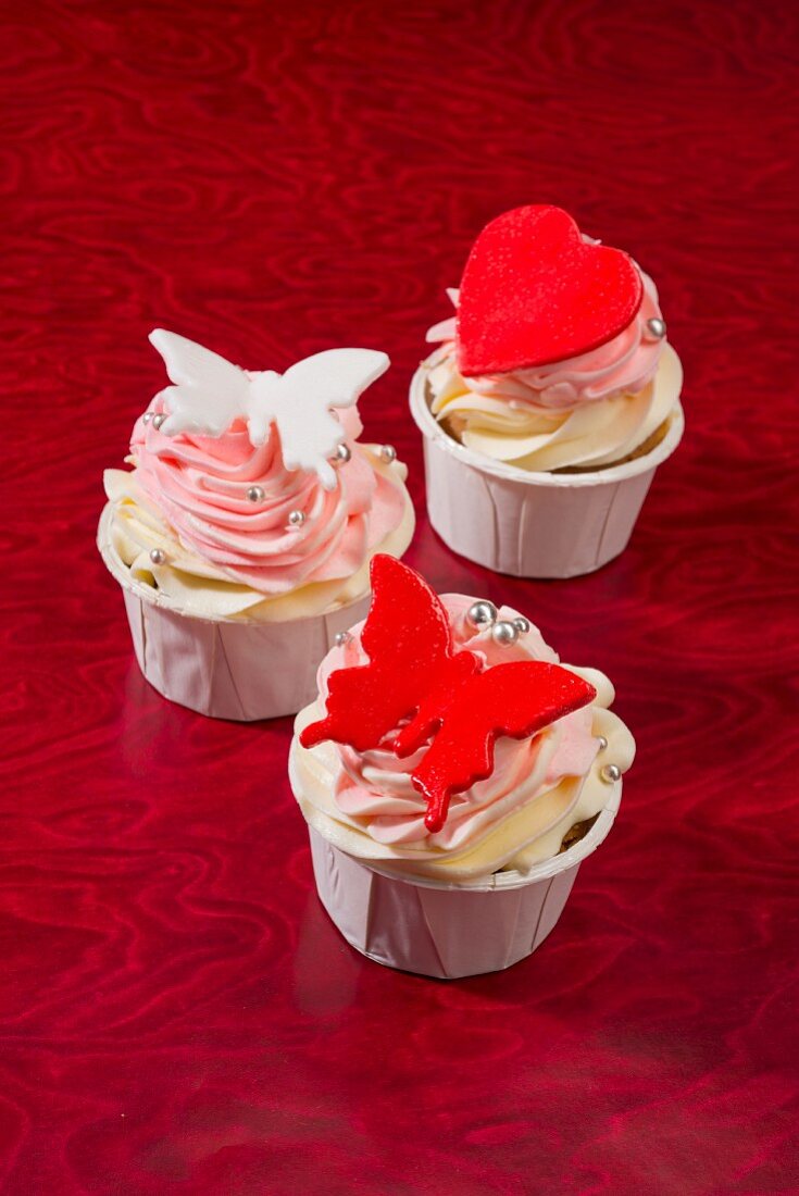 Pink cupcakes decorated with a red heart and butterflies