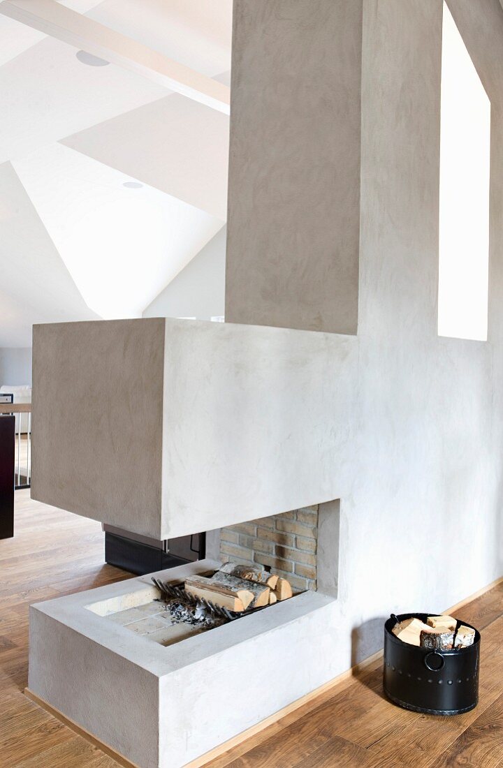 Firewood in designer, cubic, open fireplace in light-flooded attic studio