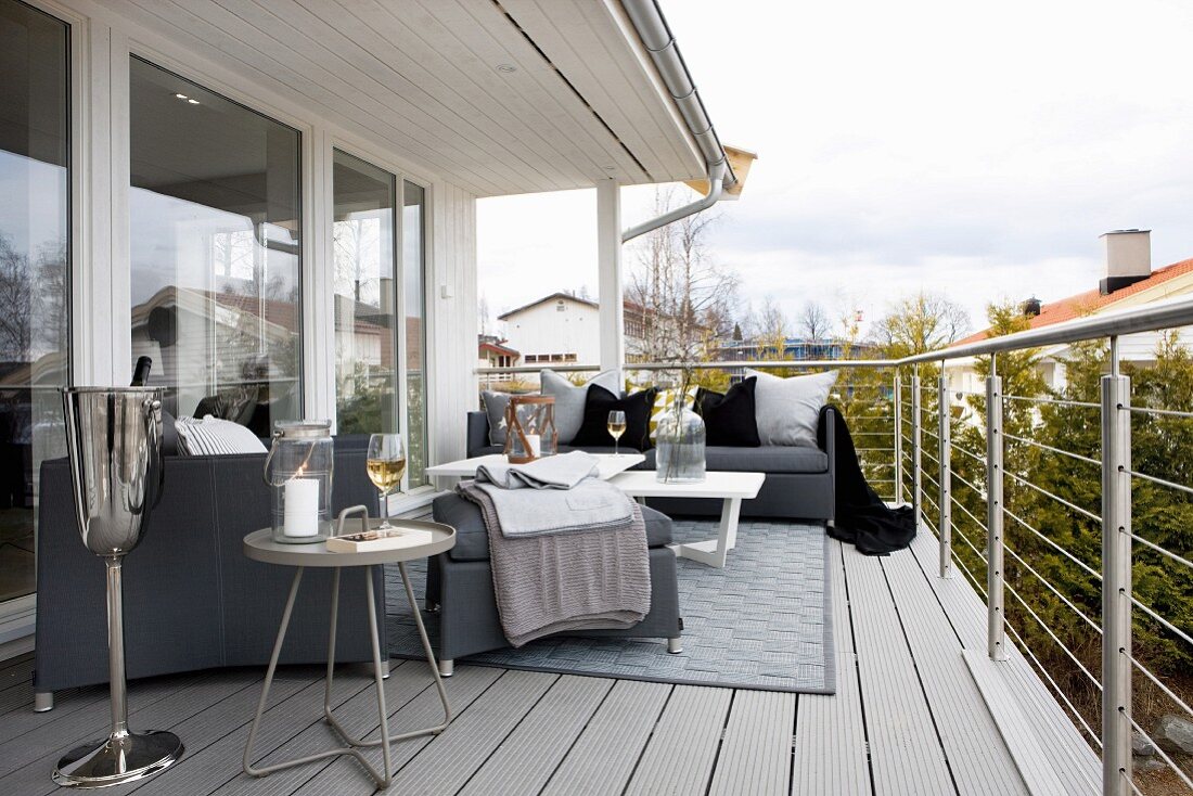 Grey sofa set, side tables and champagne cooler on wide balcony with stainless steel balustrade