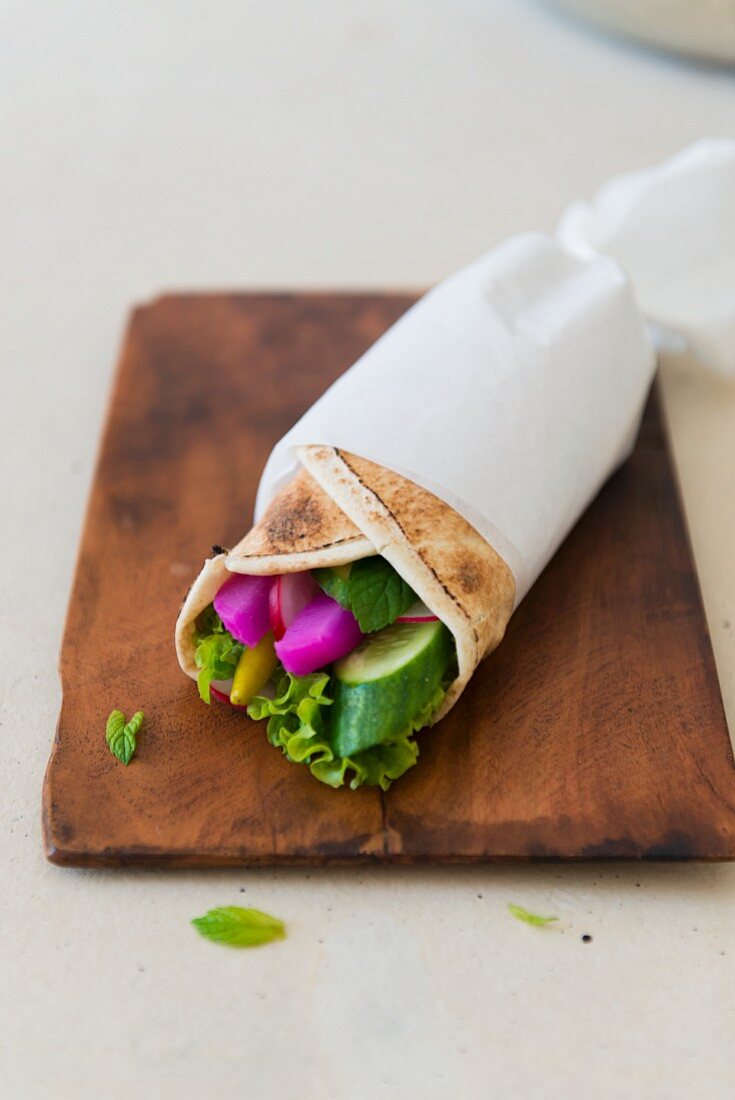 Vegetarian wrap with cucumber, salad leaves, peppermint, pickled radish and fresh radish