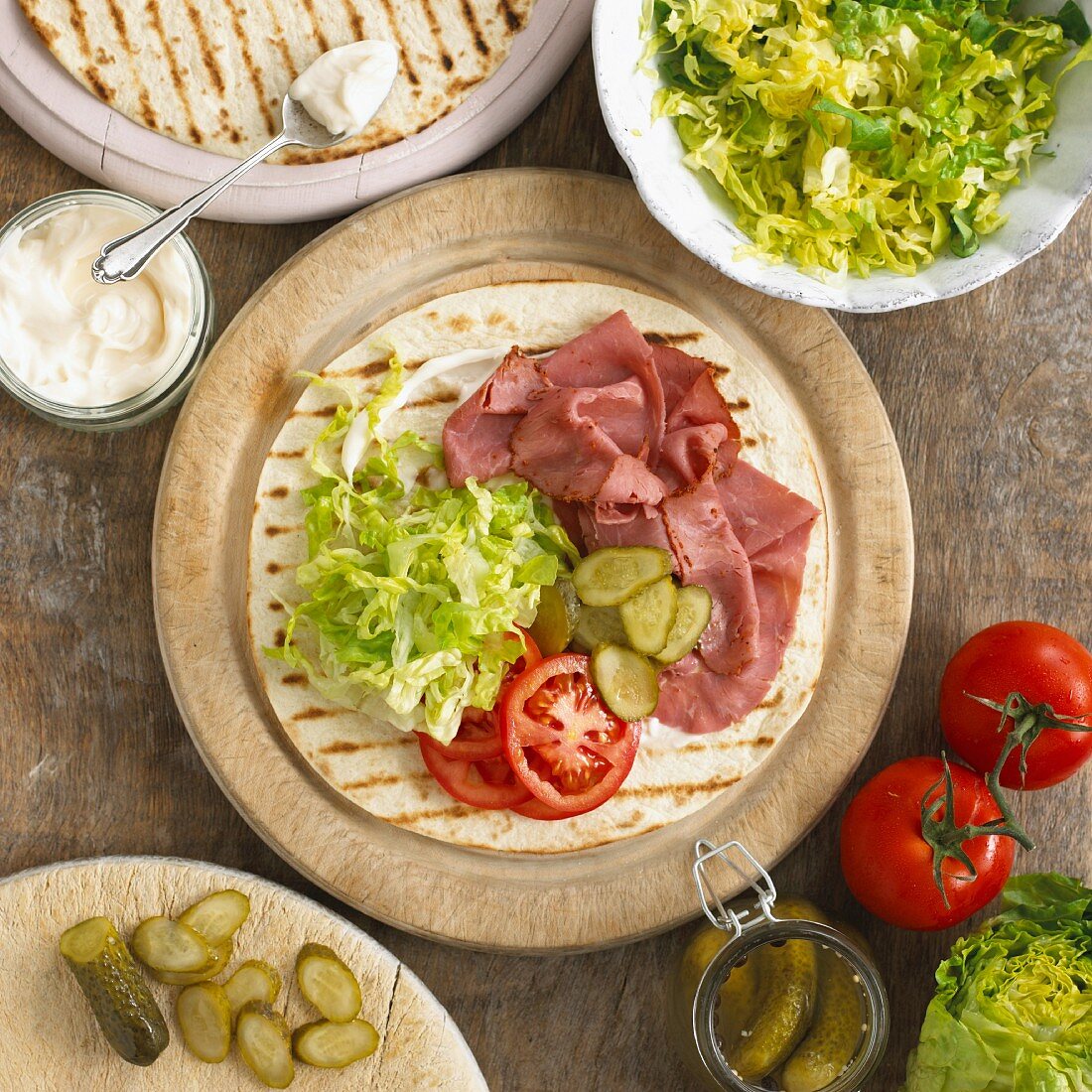 A wrap with pastrami, salad, pickled gherkins, mayonnaise and tomatoes