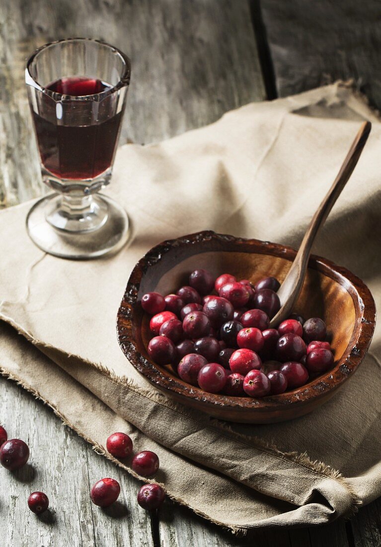 Cranberries in Holzschale und ein Glas Beerenwein