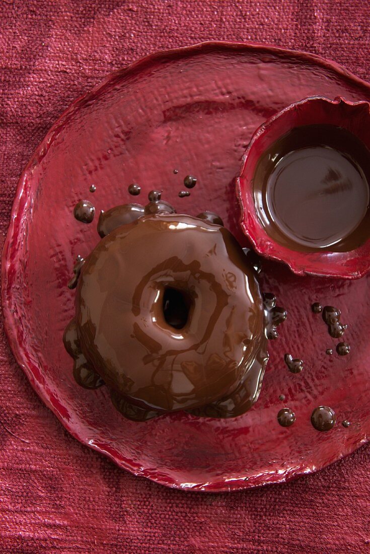 Doughnut with chocolate sauce on a red plate (view from above)