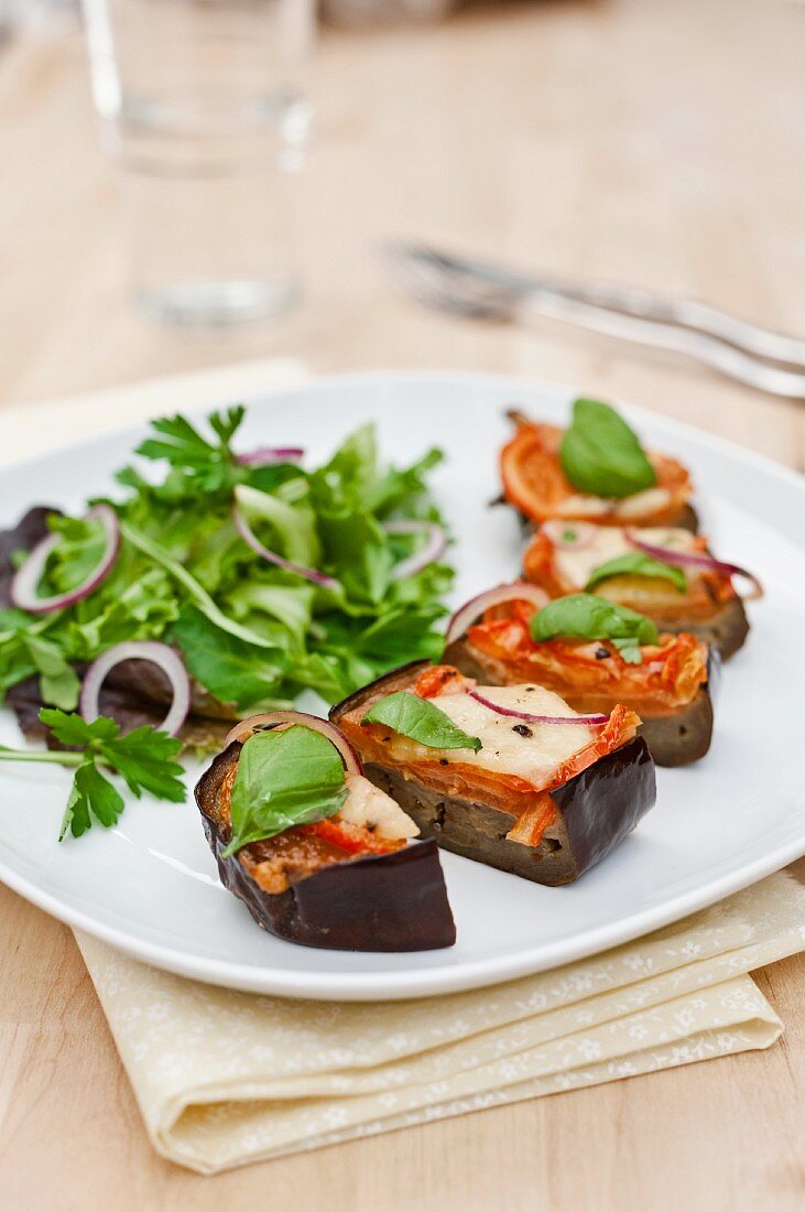 Aubergines with tomatoes and mozzarella cooked in the oven; served with a green salad