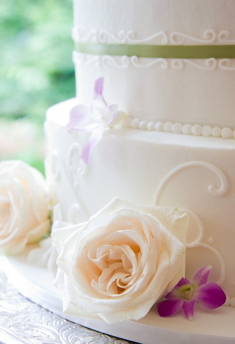 Zweistöckige weiße Hochzeitstorte dekoriert mit Rosenblüten