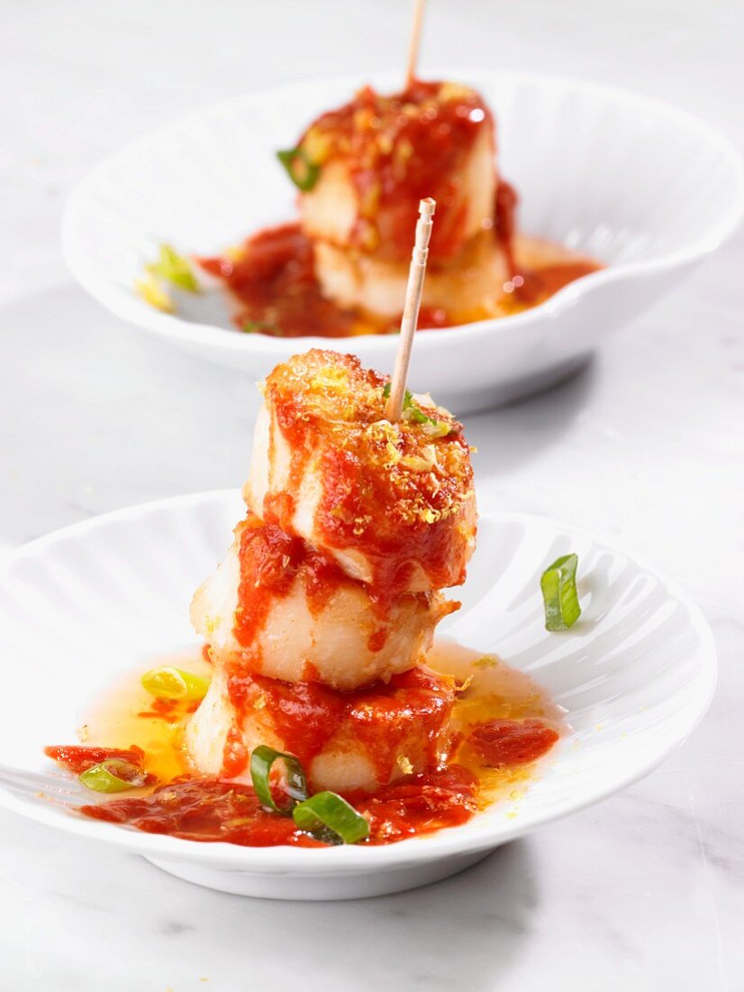 A skewer of scallops with tomato sauce