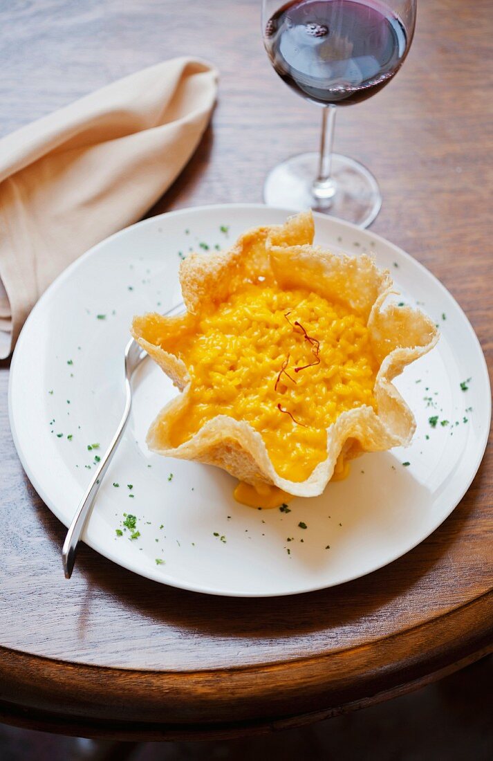 Saffron risotto in a parmesan basket and a glass of red wine
