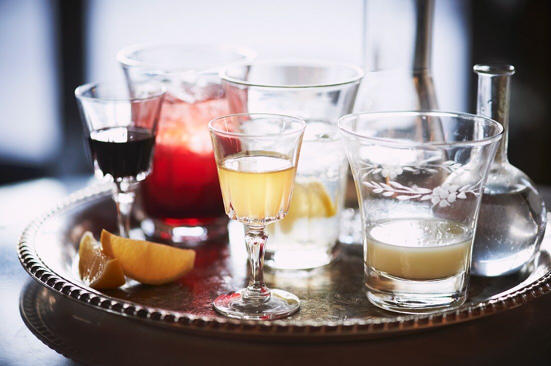 Verschiedene Drinks in Vintage-Gläsern auf Silbertablett