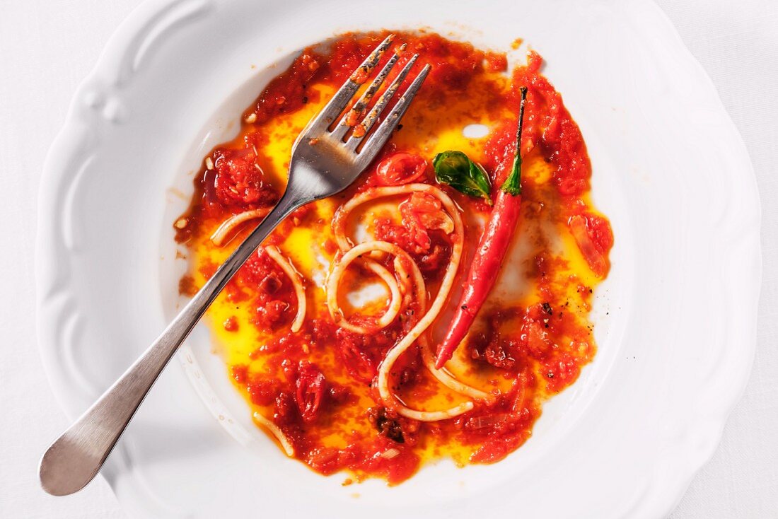 Reste von Spaghetti mit Tomaten-Chili-Sauce auf Teller