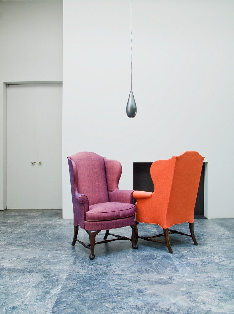 Lobby with two colorful upholstered armchairs and modern hanging light