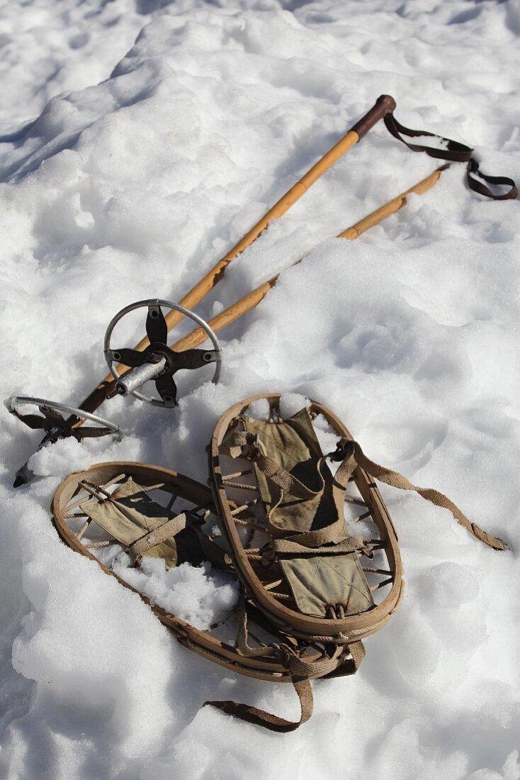 Vintage snow shoes and ski poles lying in snow