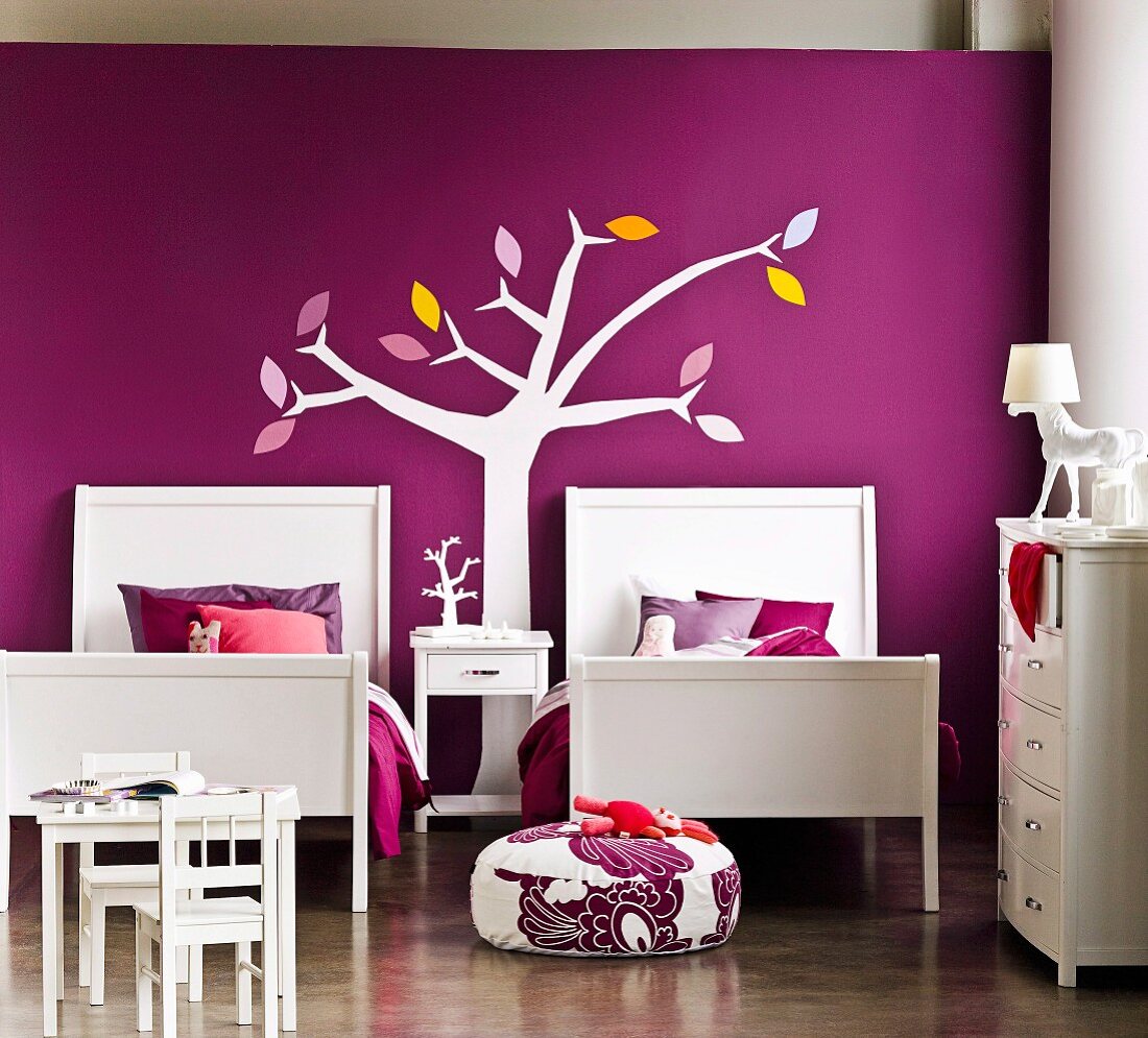 Elegant gestyltes Mädchenzimmer für ein Geschwisterpaar - zwei Betten vor violetter Wand mit stilisierter Baumdarstellung