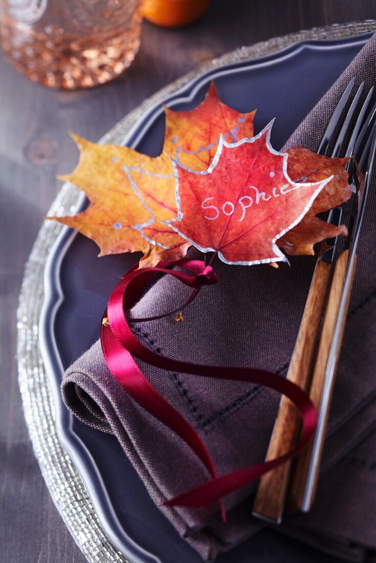 Colourful, painted autumn leaves used as name tag on plate