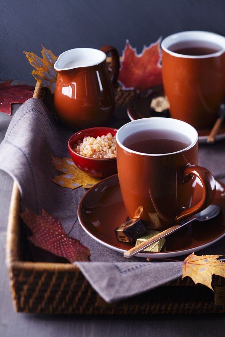 Tray of teacups, sugar and milk decorated with autumn leaves