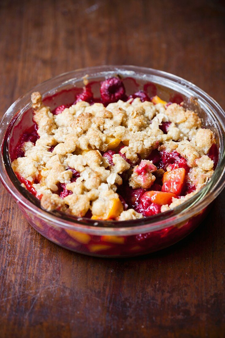 Raspberry and peach crumble in a glass dish