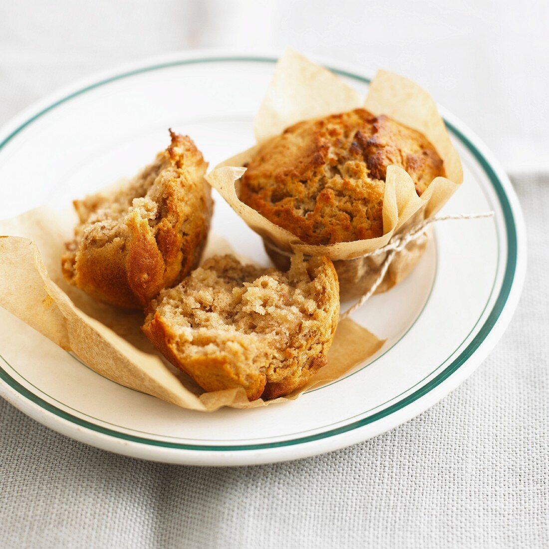 Apfel-Walnuss-Muffins im Backpapier auf Teller