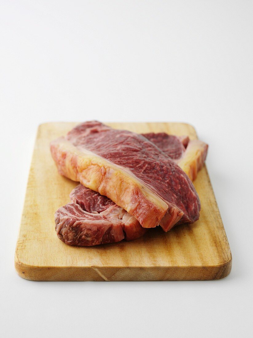 Two beef steaks on chopping board