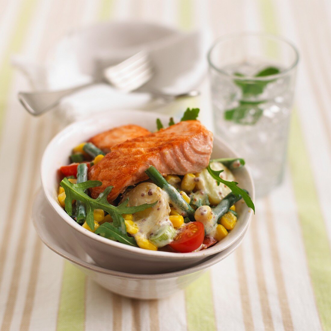 Salmon fillet on a bed of potato salad with vegetables and a mustard dressing