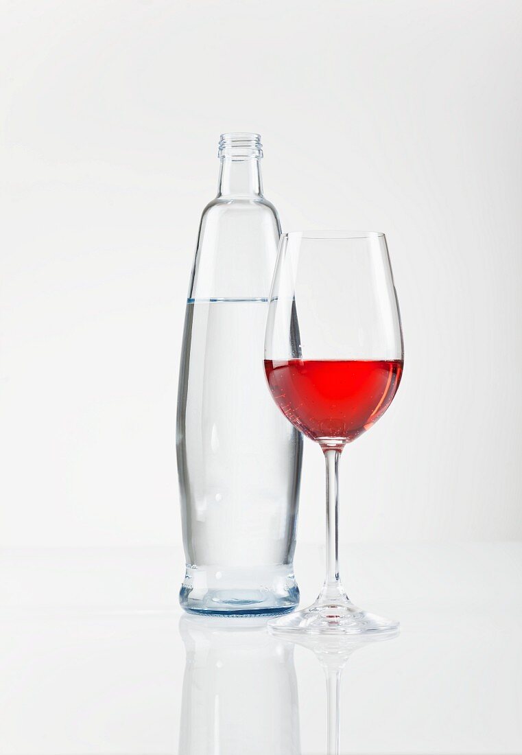 A glass of rosé wine next to a bottle of water