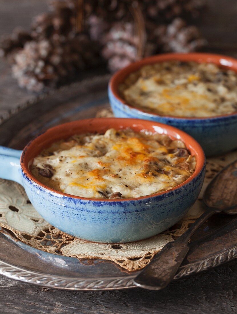 Baked Mushrooms with cheese souce in blue ceramic bowls on a silver tray