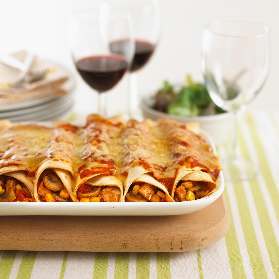 Filled tortilla rolls topped with cheese and tomato sauce and baked