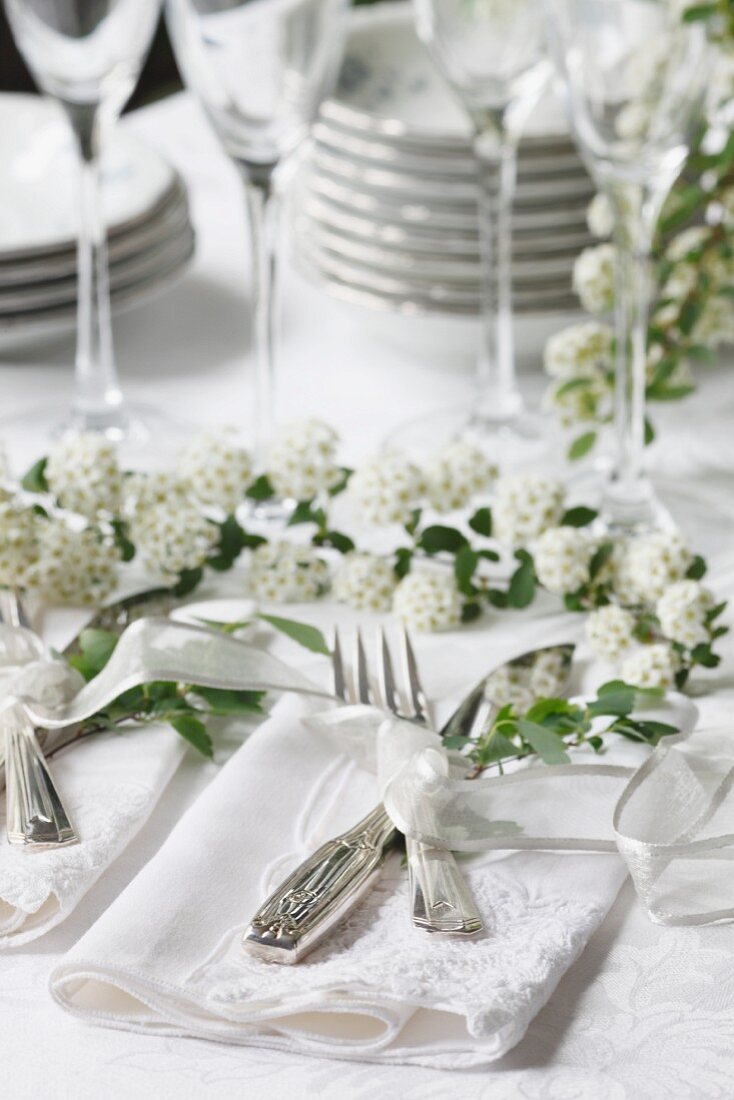 Besteck auf weisser Serviette auf einem Hochzeitstisch mit Blumendeko