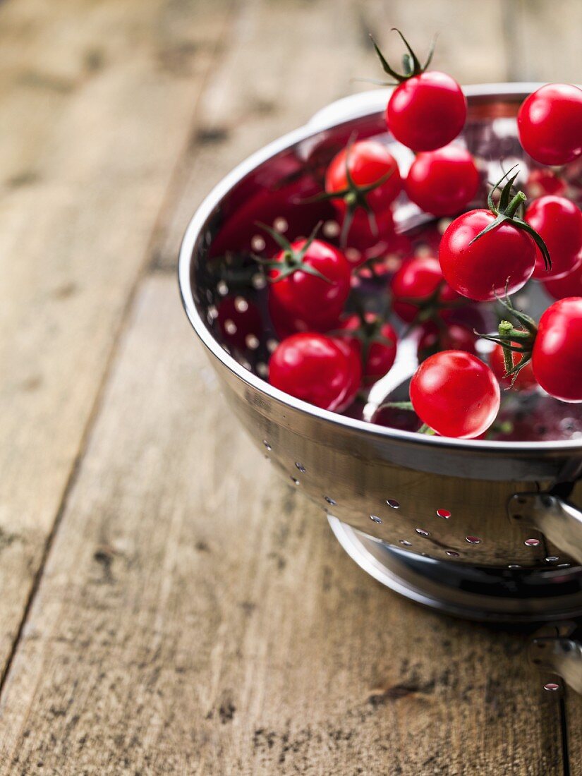Cherry tomatoes falling into a colander
