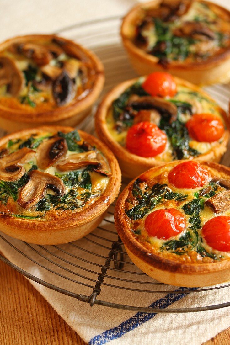 Tartlets with tomatoes, mushrooms and spinach, on a cooling rack