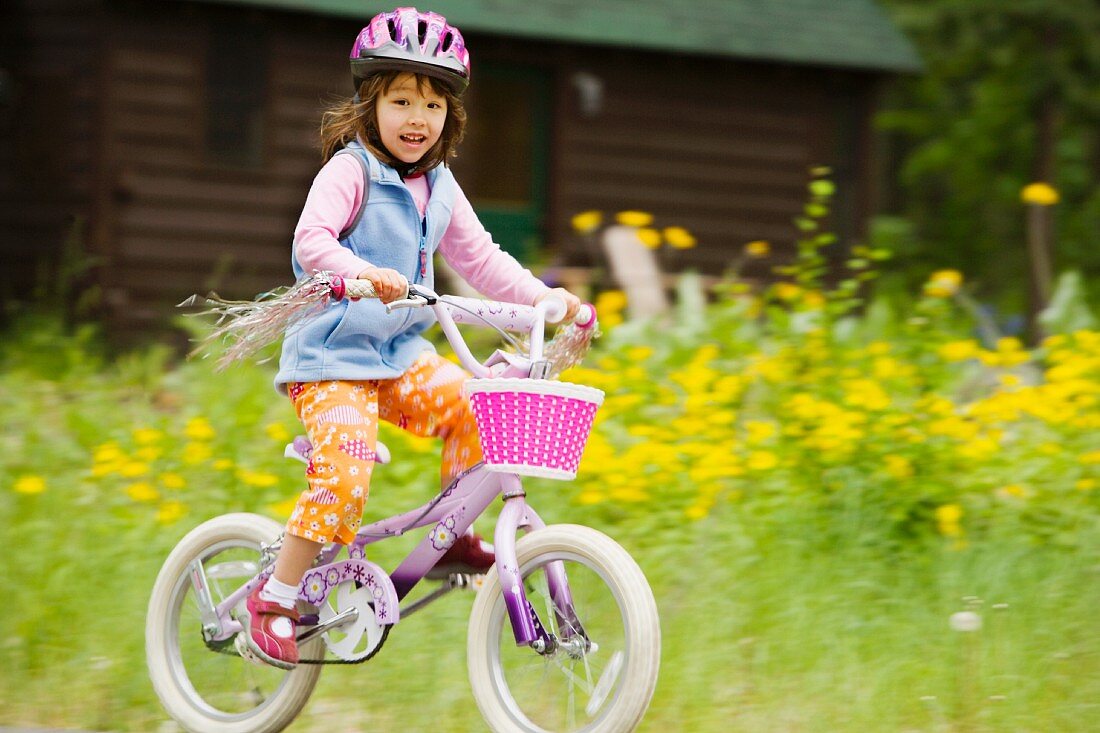Kleines Mädchen auf einem lila Fahrrad