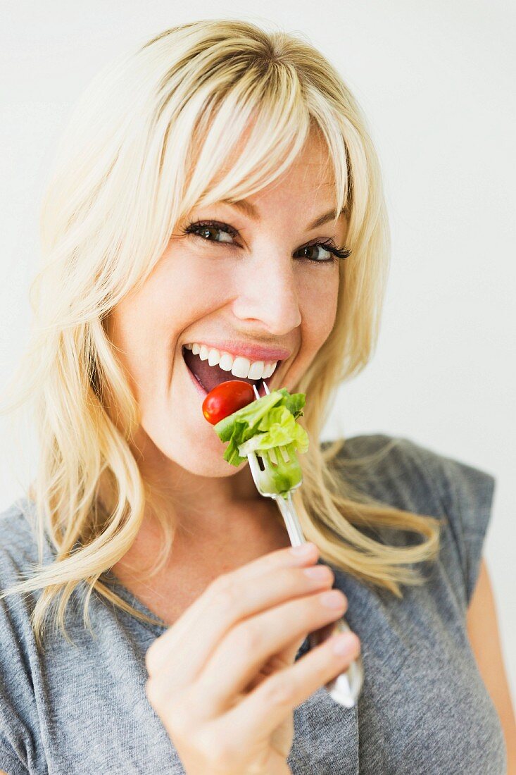 A young woman eating salad from a fork