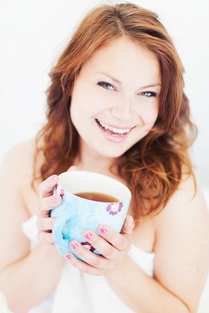 Frau mit Duschhandtuch bekleidet trinkt Tasse Kaffee