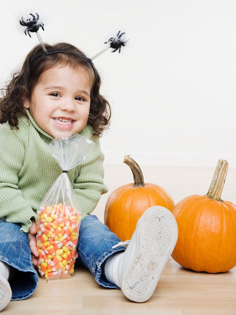 Kleines Mädchens mit Kürbissen und Süßigkeiten