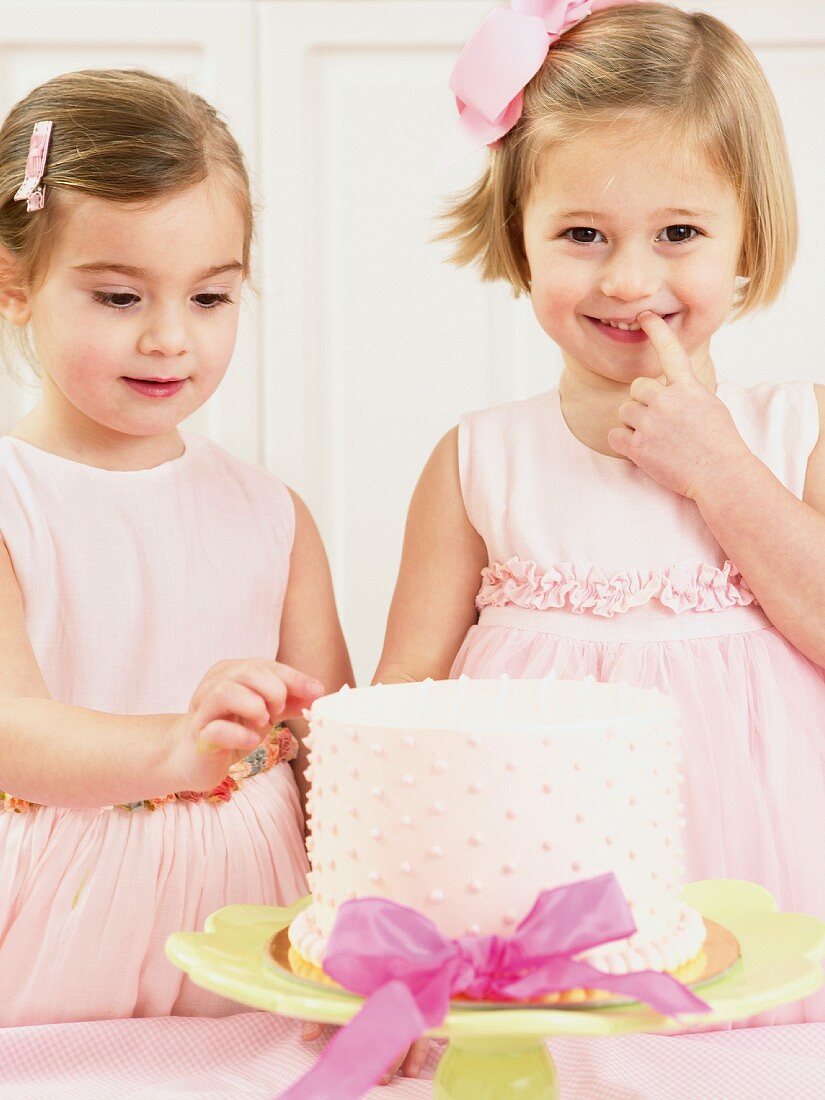 Young girls picking at a birthday cake