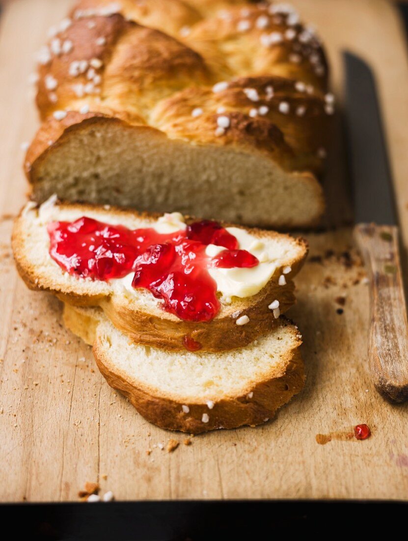 Hefezopf (sweet bread from southern Germany), partly sliced with butter and jam