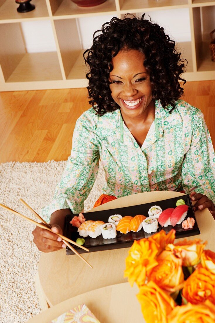 A dark-skinned woman eating sushi
