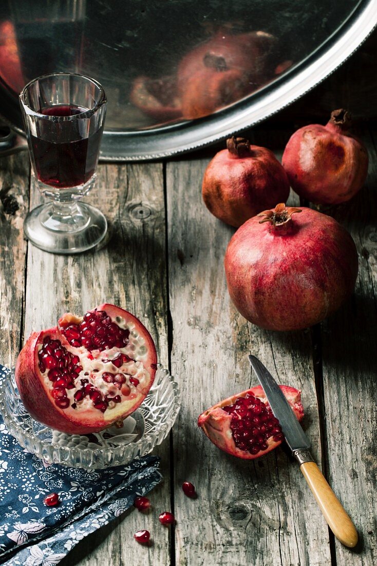 Sliced ​​pomegranate with vintage glass of red wine on wooden table