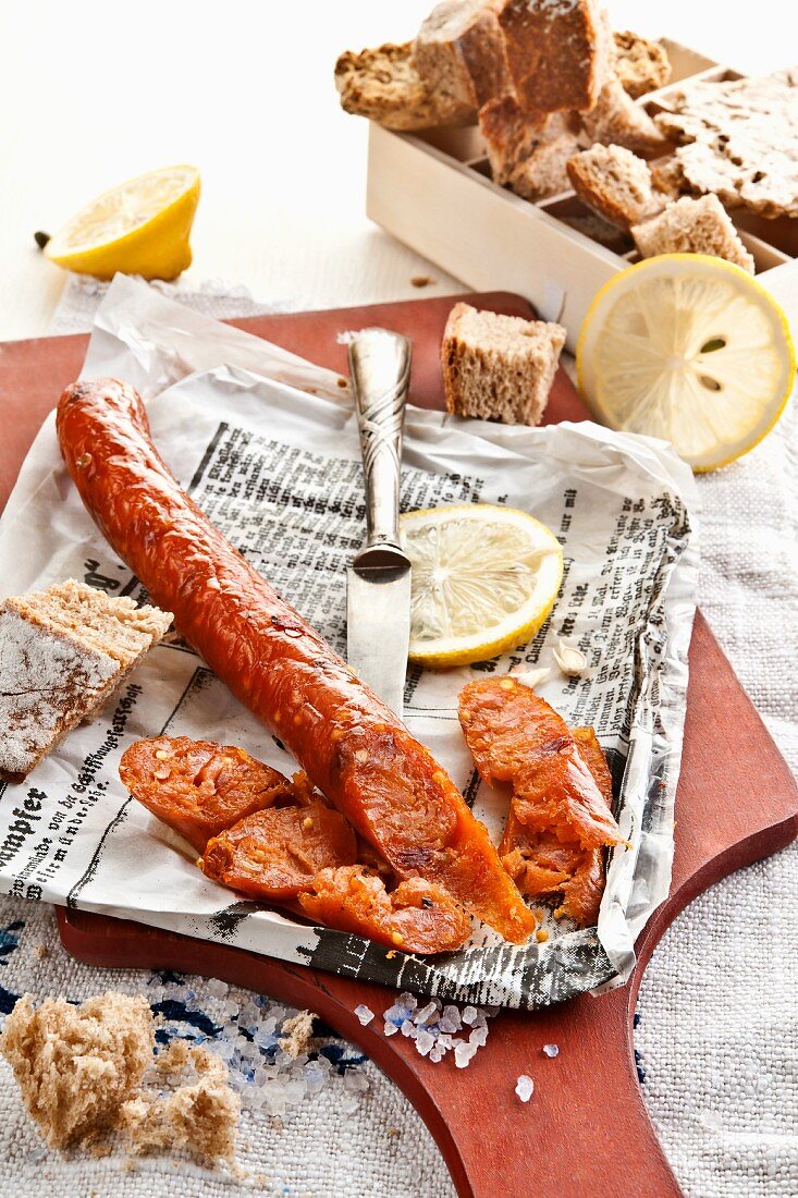 Home-made fish sausage on newspaper with lemon slices and bread
