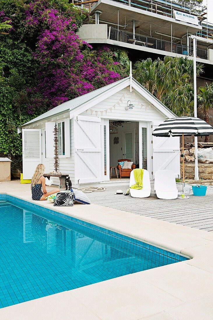 White beach cottage with spacious wooden deck next to the pool with mosaic tiles