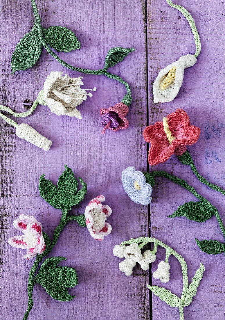 Crocheted flowers on purple wooden surface