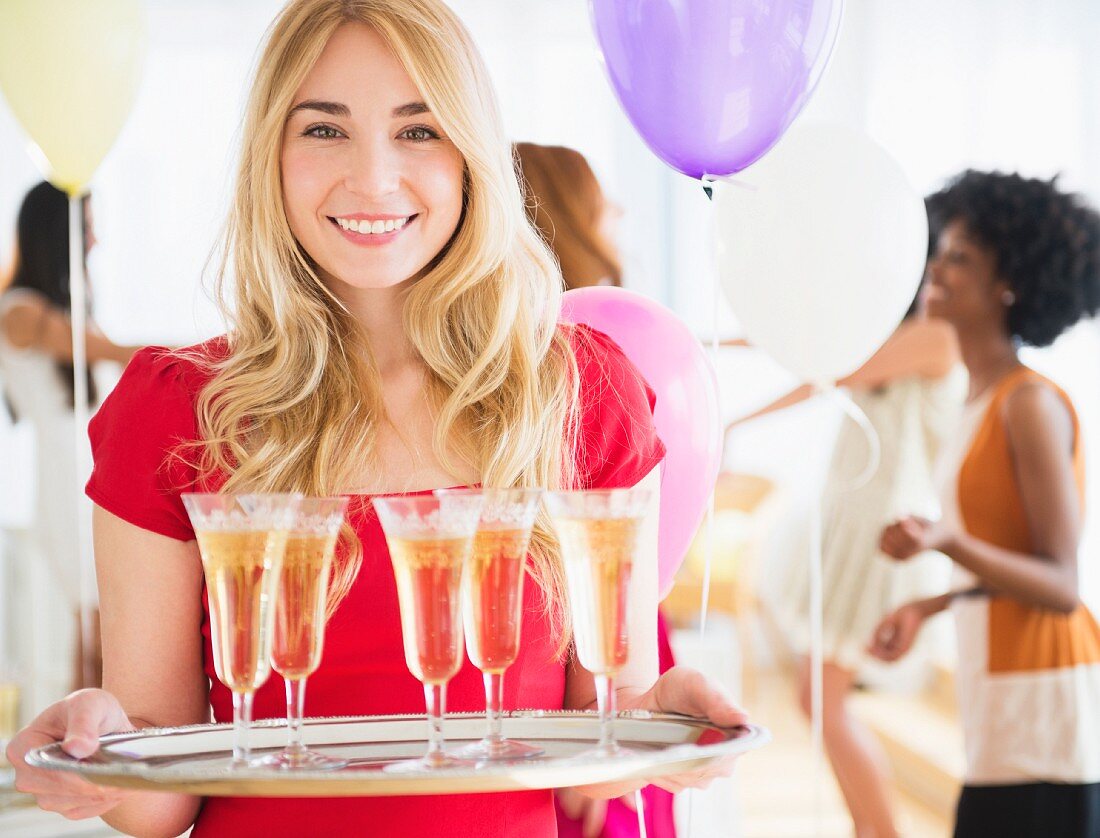Junge Frau mit gefüllten Champagnergläser auf einem Tablett
