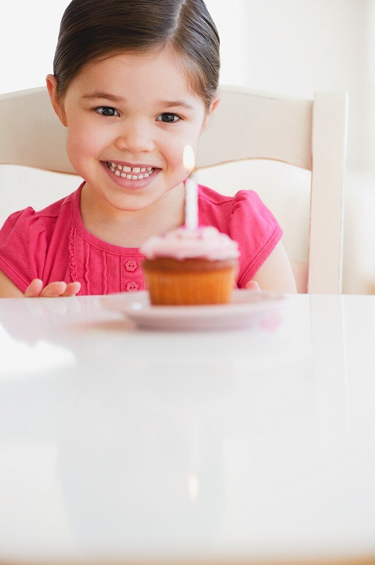 Mixed race girl looking at birthday cupcake