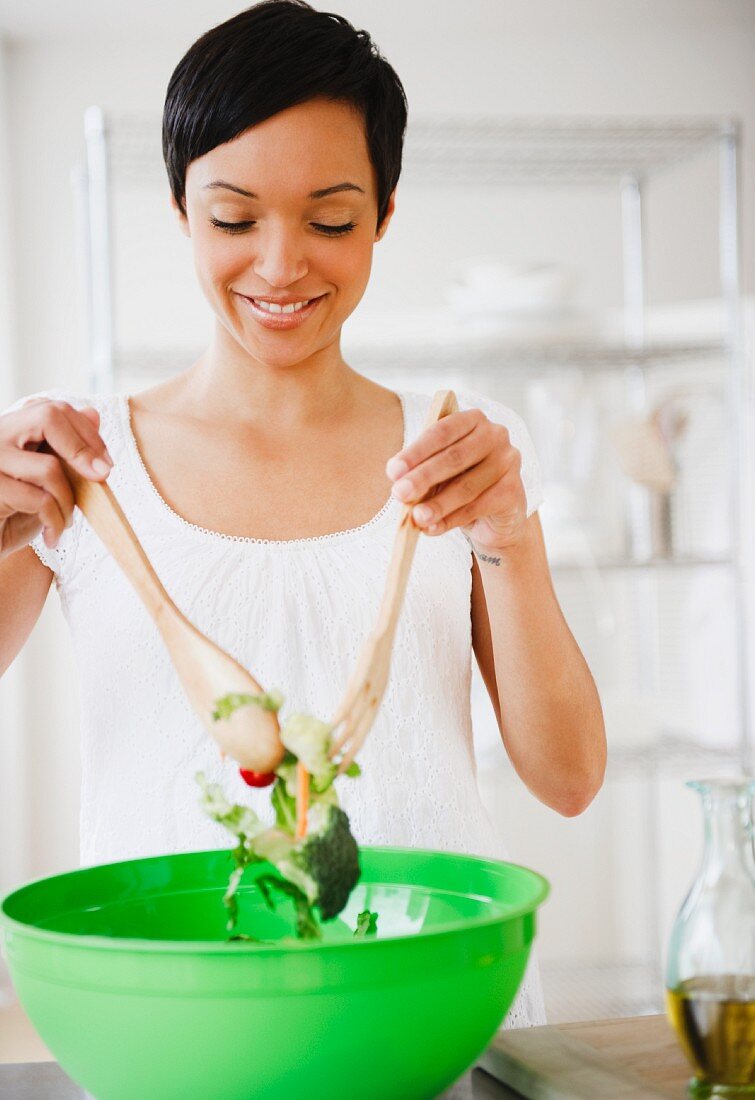 Junge Frau bereitet Salat in Salatschüssel zu