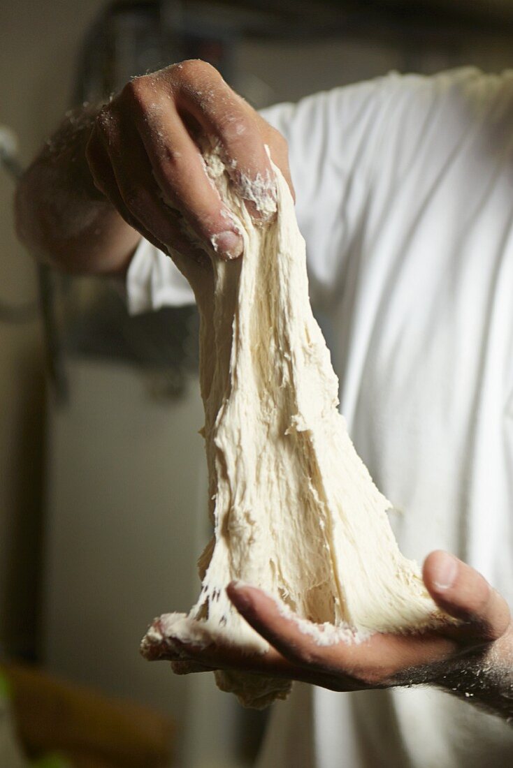 A baker pulling bread dough apart