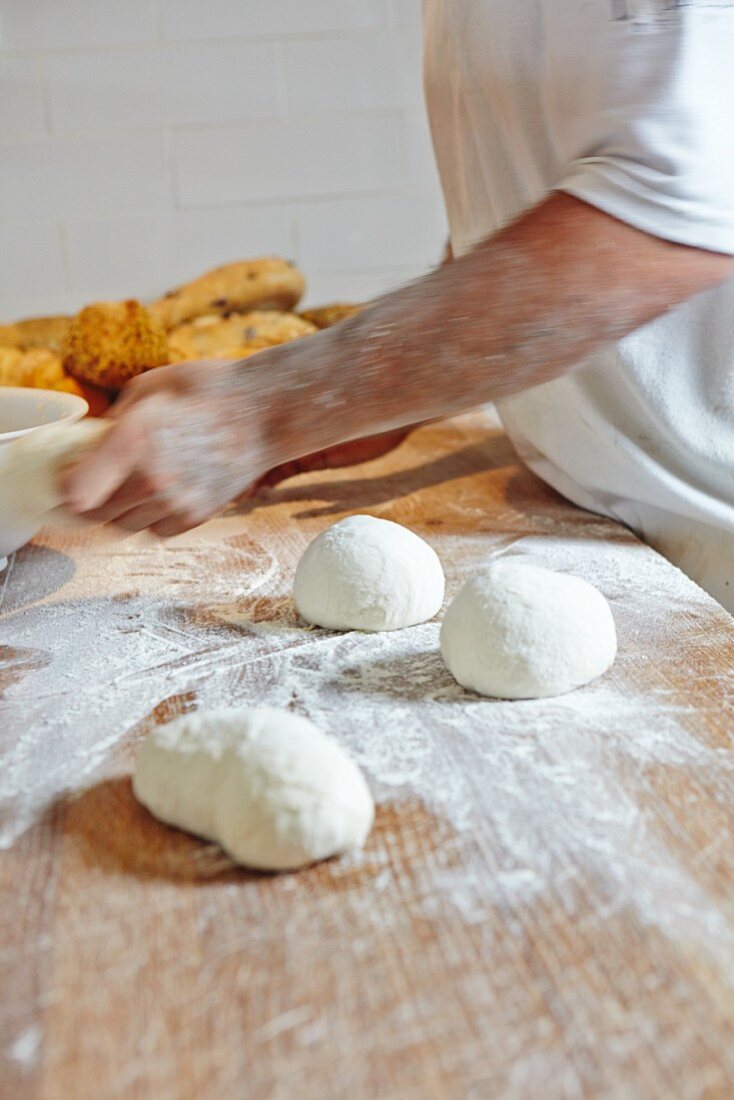 Bread dough and white loaves on a floured wooden table