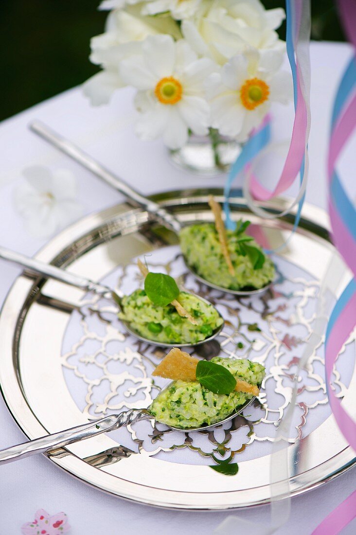 Spoon canapes with pea risotto on a silver tray for a baptism party