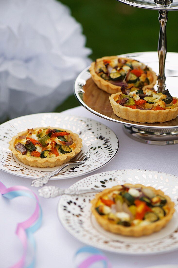 Mini vegetable quiches on a silver stand and plates